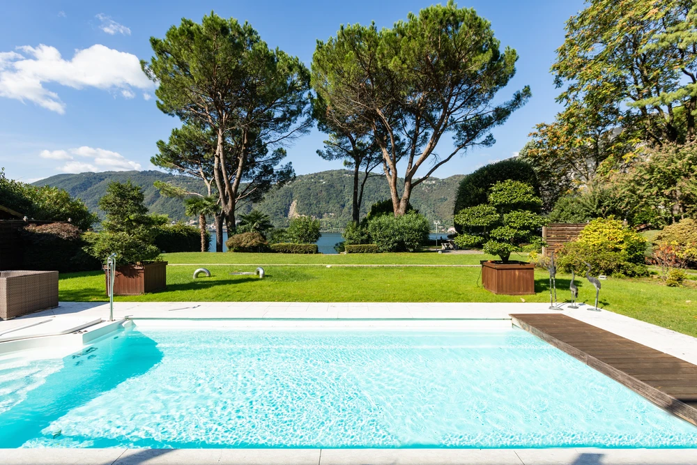 Personne tenant un kit de test chimique pour piscine en extérieur, tubes colorés indiquant les niveaux de pH, brome et chlore