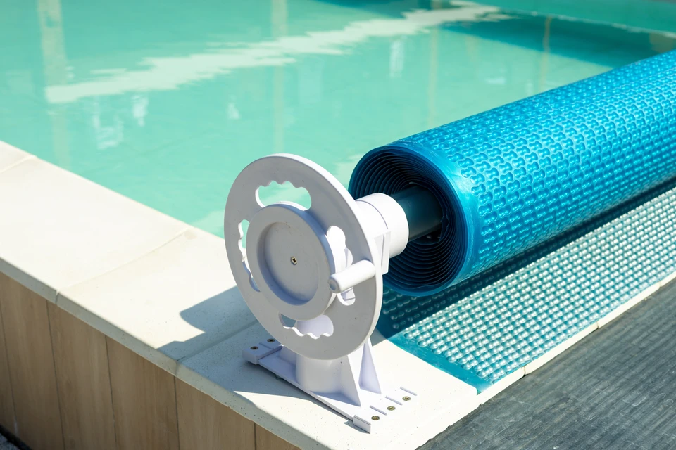 Scène extérieure au bord d'une piscine carrelée bleue avec margelles en composite marron
