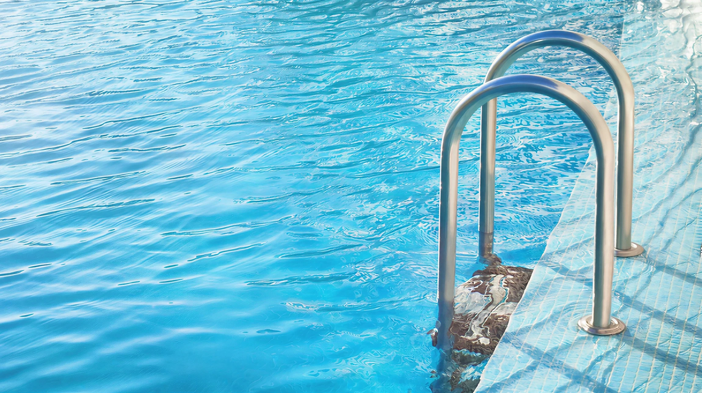 Extérieur résidentiel avec piscine rectangulaire à liner bleu, margelles en pierre claire sur terrasse pavée